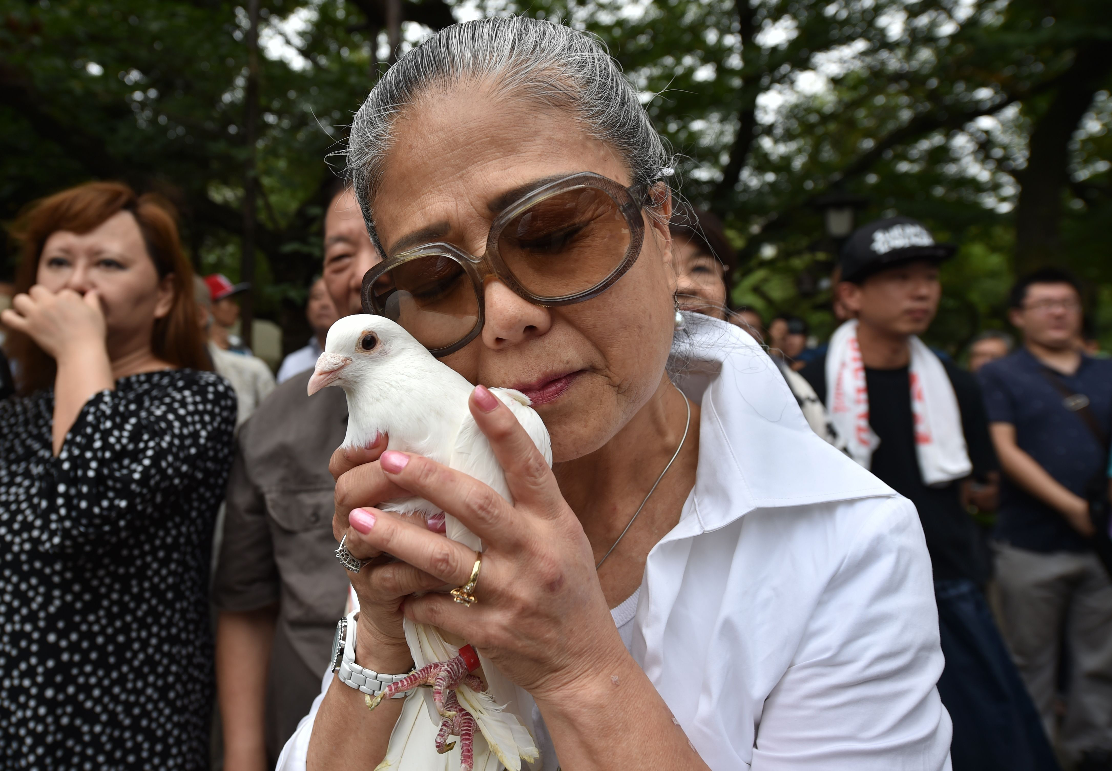 The hardest month: A woman prepares to release a dove at Yasukuni Shrine in Tokyo on Monday, on the 71st anniversary of Japan's World War II surrender. | AFP-JIJI